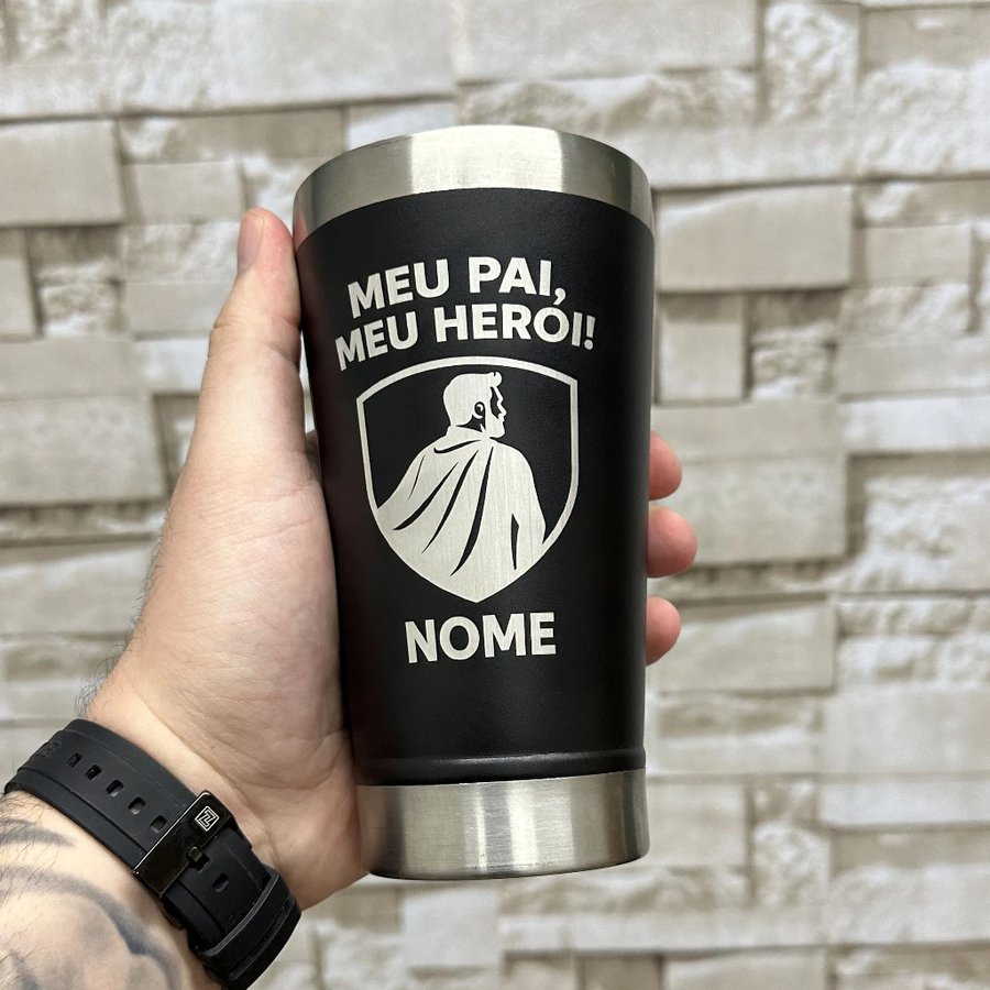 Mão segurando copo térmico preto personalizado com a frase meu pai meu herói e escudo de super-herói gravado em inox