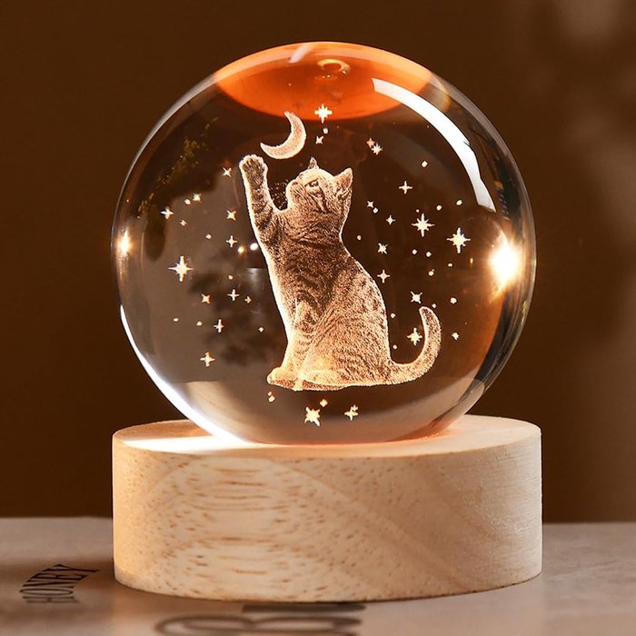 Bola de cristal com gato gravado a laser em 3D sobre base iluminada